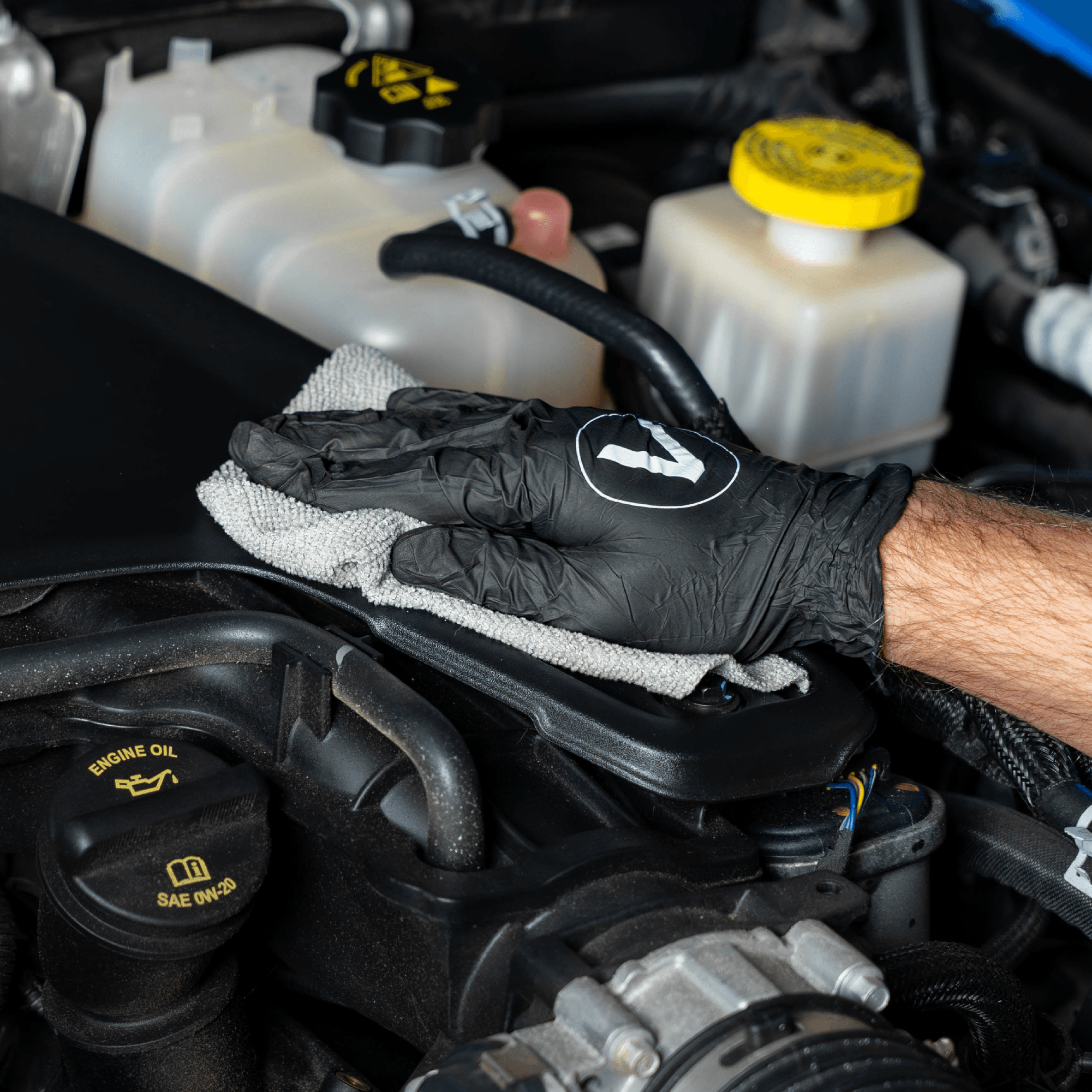 Person cleaning a car engine with a VIKING microfiber cloth.