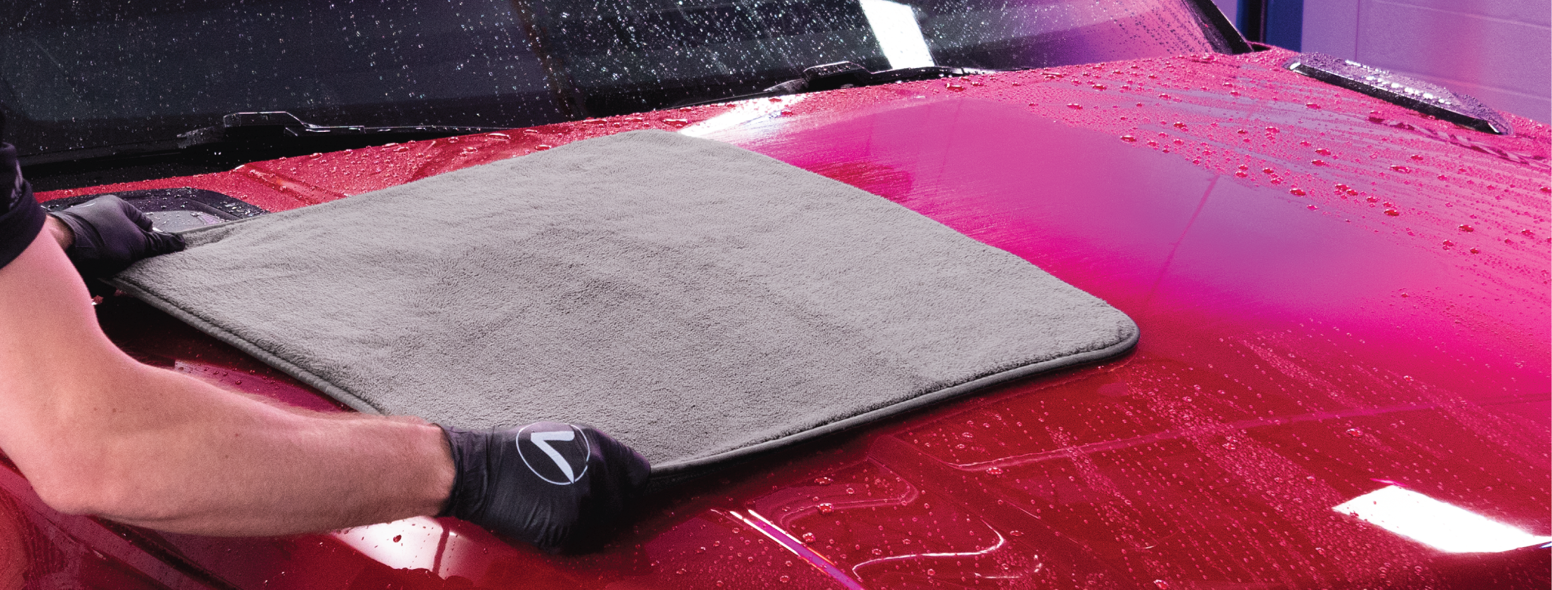 pulling drying towel across hood of red vehicle