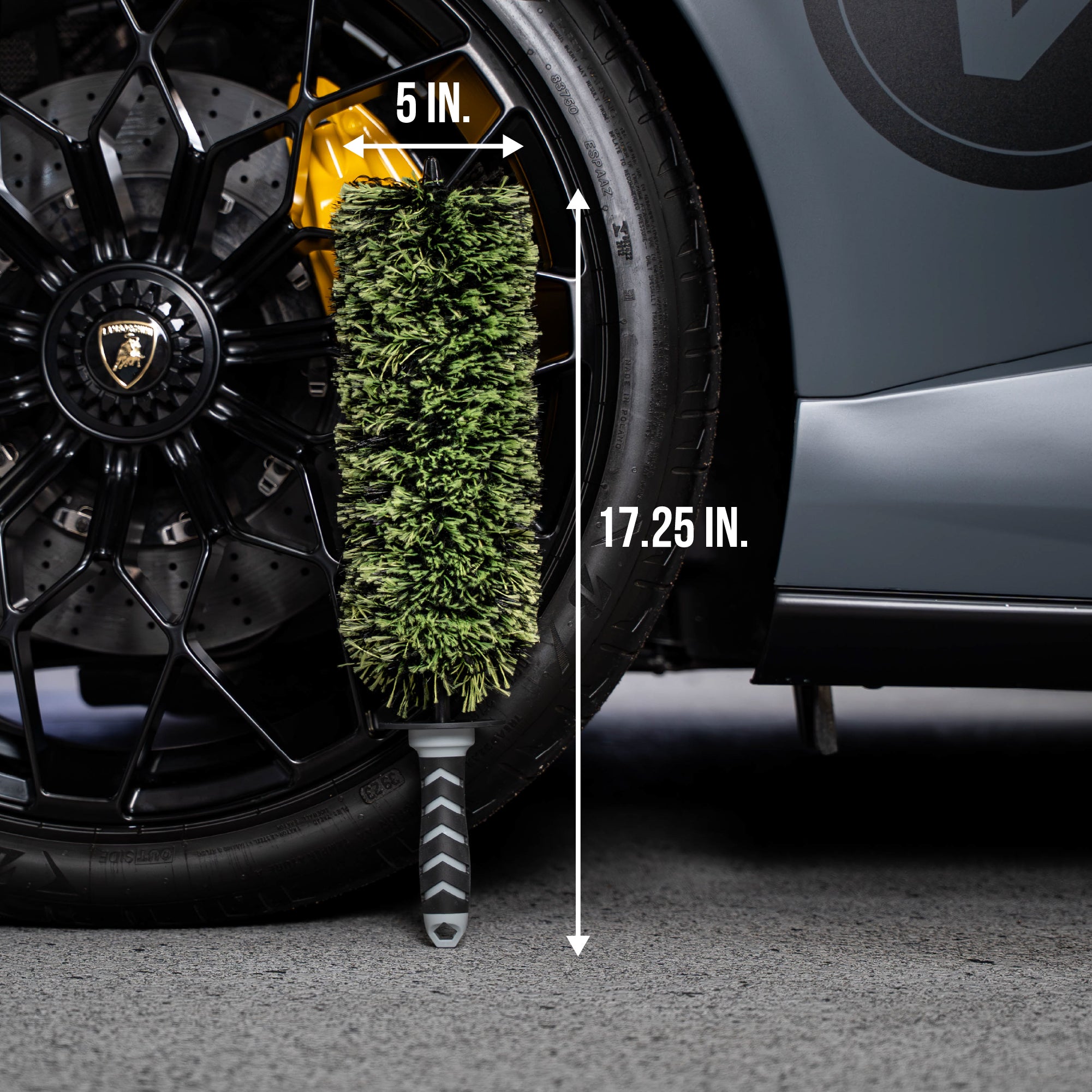 Car tire with a brush next to it, showing dimensions, against a car background.